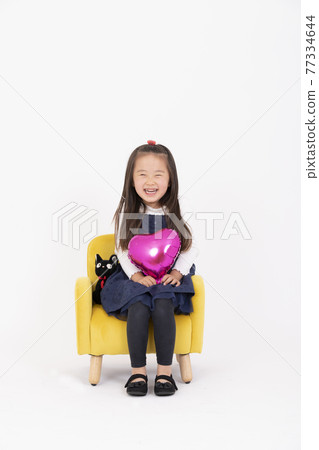 一個微笑的女孩坐在椅子上 一個微笑的女孩坐在椅子上 77334644