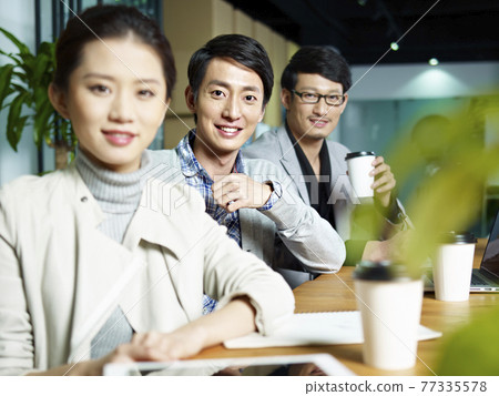 a team of young asian entrepreneurs posing in meeting room, focus on the young man in middle a team of young asian entrepreneurs posing in meeting room, focus on the young man in middle 77335578
