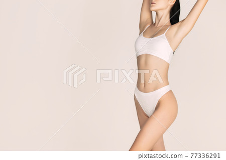 Cropped slim tanned beautiful woman in underwear isolated over light background. Cropped slim tanned beautiful woman in underwear isolated over light background. 77336291