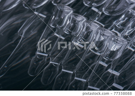 Glass medical ampoule vial for injection. Medicine is liquid sodium chloride with of aqueous solution in ampulla. Close up. Bottles ampule multicolor. Glass medical ampoule vial for injection. Medicine is liquid sodium chloride with of aqueous solution in ampulla. Close up. Bottles ampule multicolor. 77338088