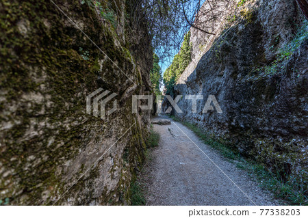 Narrow and long path between huge rocks 77338203