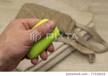 A piece of soap in hand on background of a terry towel and washcloth A piece of soap in hand on background of a terry towel and washcloth 77338838