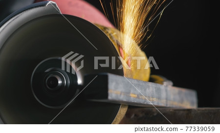Forge workshop. Smithy manual production. Close up details of sparks, industrial worker using angle grinder and cutting steel. Forge workshop. Smithy manual production. Close up details of sparks, industrial worker using angle grinder and cutting steel. 77339059