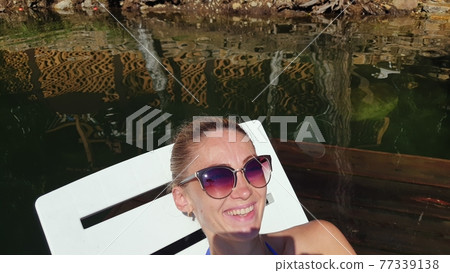Woman shooting self portrait. Take photo and video on smartphone. Girl rest, relax, walk in sunglasses, make selfie. Blogger broadcast video vlogging. 77339138