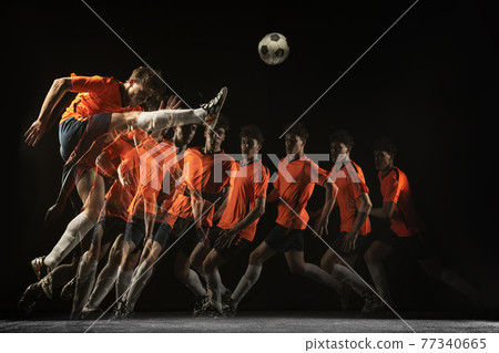 Young male football soccer player in motion and action in mixed light on dark background. Young male football soccer player in motion and action in mixed light on dark background. 77340665
