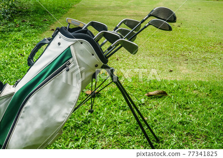 Closeup old golf bags on green. Set of golf clubs over green field background. 77341825