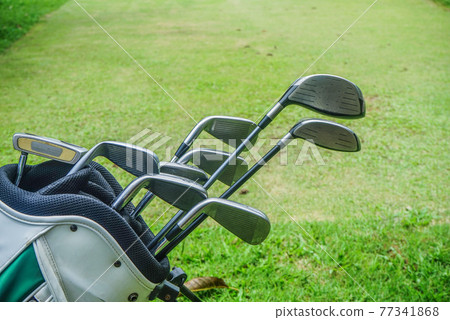 Closeup old golf bags on green. Set of golf clubs over green field background. 77341868