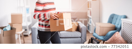 Woman carrying cardboard box in her hands 77342051