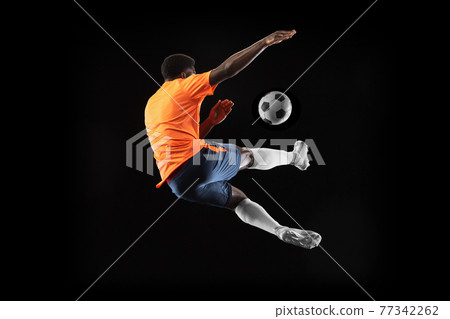 Young African football soccer player playing isolated on black background. Concept of sport, movement, energy and dynamic. 77342262
