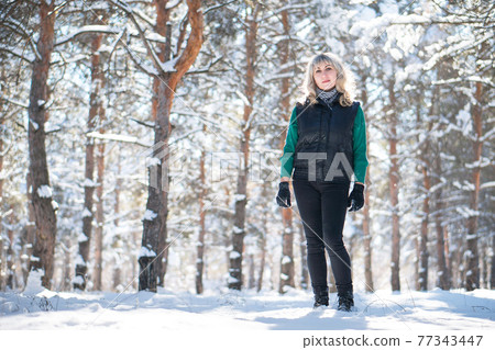 Woman in snowy forest in winter time. 77343447