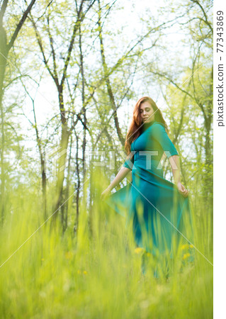 Beautiful young woman dance in forest on blurred green background. Beautiful young woman dance in forest on blurred green background. 77343869