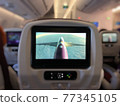 In flight head rest screen showing a picture from flight camera, an airplane is flying above the clouds. Travel is pleasure. 77345105