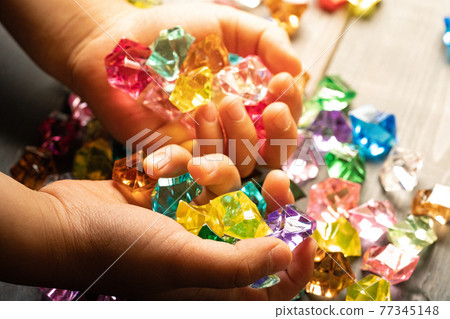 Children's hands playing with colorful acrylic stones 77345148