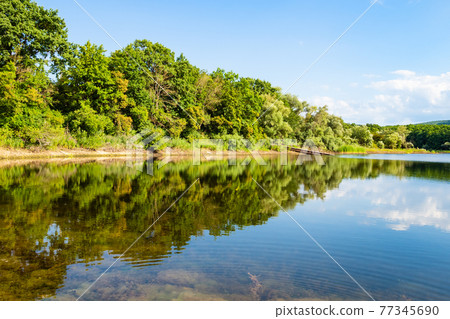 view of karst lake in forest at summer sunset view of karst lake in forest at summer sunset 77345690