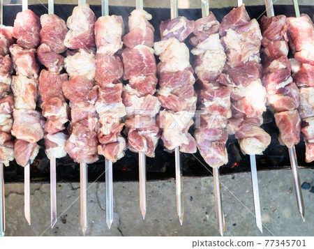 raw skewered shish kebabs on brazier with hot coal 77345701