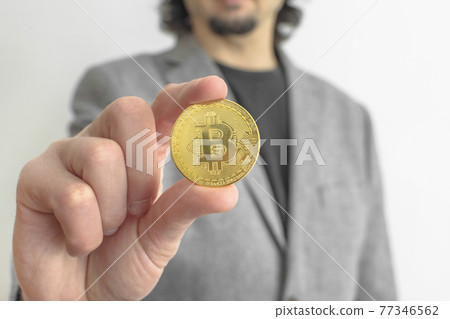 Businessman wearing a suit, holding a Bitcoin BTC crypto currency gold coin, new virtual money concept. Mining or blockchain technology Businessman wearing a suit, holding a Bitcoin BTC crypto currency gold coin, new virtual money concept. Mining or blockchain technology 77346562