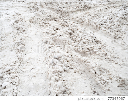 snowy ruts on snow covered surface of city road snowy ruts on snow covered surface of city road 77347067