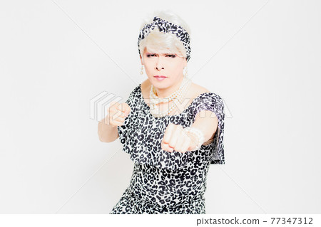 Drag queen standing in front of a white background and making a punch gesture Drag queen standing in front of a white background and making a punch gesture 77347312