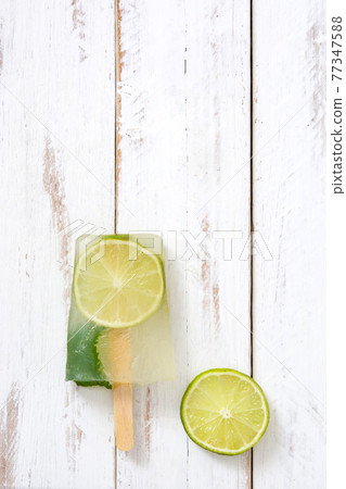 Lime popsicle on white wooden table 77347588