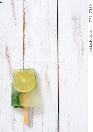 Lime popsicle on white wooden table 77347589