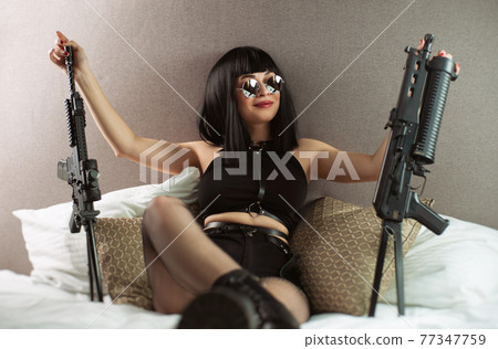 portrait of a female assassin with an automatic rifle in round glasses on the bed portrait of a female assassin with an automatic rifle in round glasses on the bed 77347759