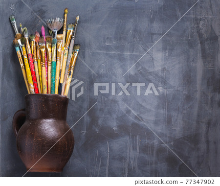 Paint brush in clay jug or pot on abstract table background texture Paint brush in clay jug or pot on abstract table background texture 77347902