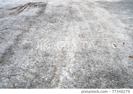frozen road with fallen leaves after freezing rain 77348279