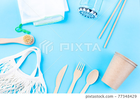 Zero waste or plastic free concept, wooden and paper utensil, reusable bags and glass, on blue background, horizontal, top view, copy space 77348429
