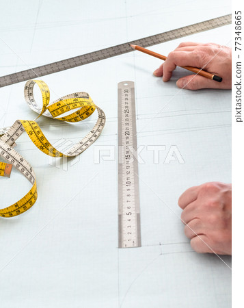 tailor's hands , measuring tape, rulers and pencil tailor's hands , measuring tape, rulers and pencil 77348665