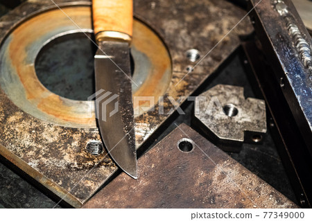 blade of forged knife close up on metal workbench 77349000