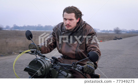 A furious anger motorbike rider fast moving country road on sunny windy day. A furious anger motorbike rider fast moving country road on sunny windy day. 77349275