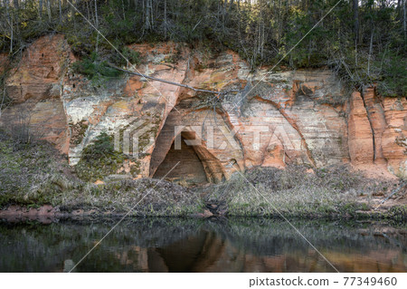 Red sandstones cliffs angel cave at the river Salaca Red sandstones cliffs angel cave at the river Salaca 77349460