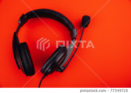 Black headphones isolated on red background 77349728