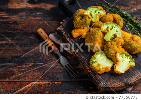 Crumbed broccoli steaks on a wooden board. Dark wooden background. Top view. Copy space Crumbed broccoli steaks on a wooden board. Dark wooden background. Top view. Copy space 77350775