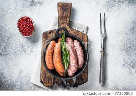 Assorted Raw sausages Chorizo and Bratwurst with spices in a pan with rosemary. White background. Top View Assorted Raw sausages Chorizo and Bratwurst with spices in a pan with rosemary. White background. Top View 77350806