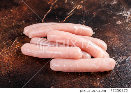 Raw chicken and turkey meat sausages on butcher table. Dark background. Top view Raw chicken and turkey meat sausages on butcher table. Dark background. Top view 77350875