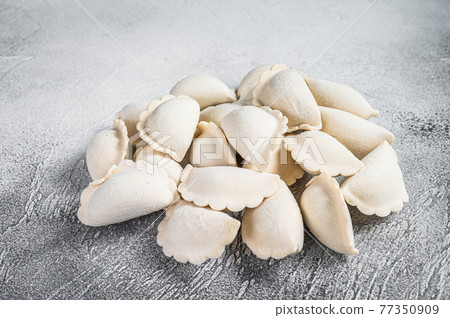 Raw frozen dumplings pierogi on a kitchen table. White background. Top View Raw frozen dumplings pierogi on a kitchen table. White background. Top View 77350909