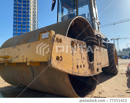 Road repair, compactor lays asphalt. Heavy special machines. Asphalt paver in operation. Side view. Closeup 77351423