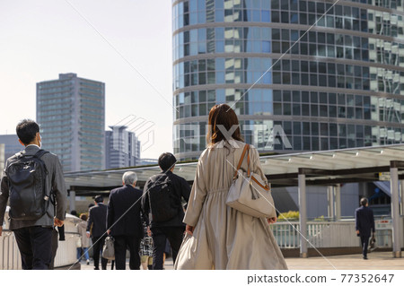Back view of a walking woman commuting in the morning 77352647