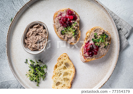Toasts with chicken rillettes pate on white bread with sprouts. White background. Top View Toasts with chicken rillettes pate on white bread with sprouts. White background. Top View 77354379