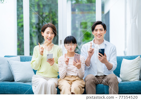 客廳裡有智能手機的中產家庭 客廳裡有智能手機的中產家庭 77354520