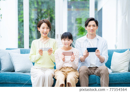 客廳裡有智能手機的中產家庭 客廳裡有智能手機的中產家庭 77354564