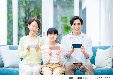 客廳裡有智能手機的中產家庭 客廳裡有智能手機的中產家庭 77354567