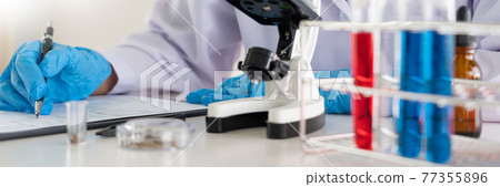 scientists researching in laboratory in white lab coat, gloves analysing, looking at test tubes sample, biotechnology concept 77355896