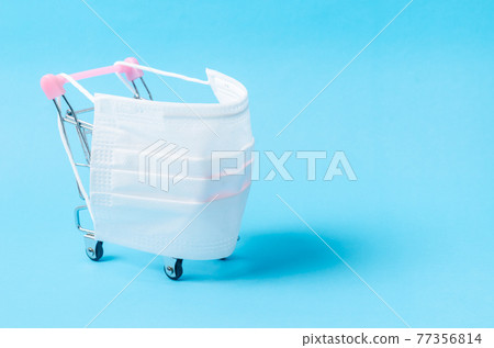 Disposable face mask medical and shopping cart on color background with empty space. 77356814