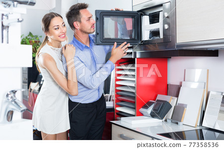 Husband and wife are choosing new microwave 77358536