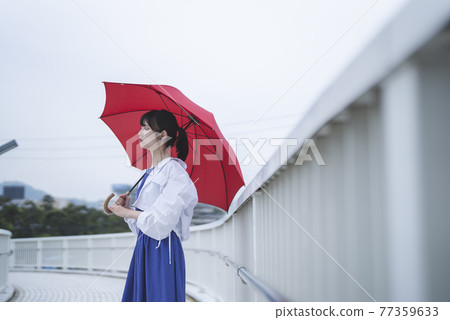 A woman holding an umbrella on a rainy day 77359633