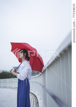 A woman holding an umbrella on a rainy day 77359635