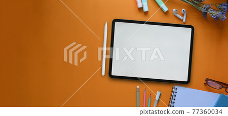 Top view image of white blank screen computer tablet, glasses, marker pens, pencils, notebook and flowers that putting together on colorful working desk. Orderly workspace concept. Top view image of white blank screen computer tablet, glasses, marker pens, pencils, notebook and flowers that putting together on colorful working desk. Orderly workspace concept. 77360034