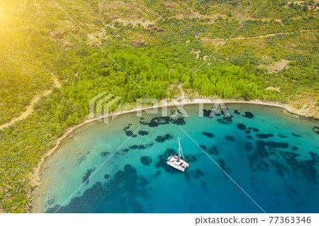 Aerial view of a catamaran yacht in the blue sea. Yachting, luxury vacation at sea. Aerial view of a catamaran yacht in the blue sea. Yachting, luxury vacation at sea. 77363346